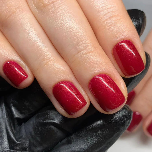 Hand wearing Bio Sculpture Gemini Nail Polish No. 21 Ravishing Ruby – vegan, burgundy red polish with a subtle sheen for a chic, sophisticated nail look