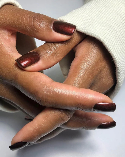 Fingers painted with Bio Sculpture Gemini Nail Polish No. 213 Rosewood Stardust on dark skin – non-toxic, rosewood pink polish with subtle sparkle for a chic, versatile look