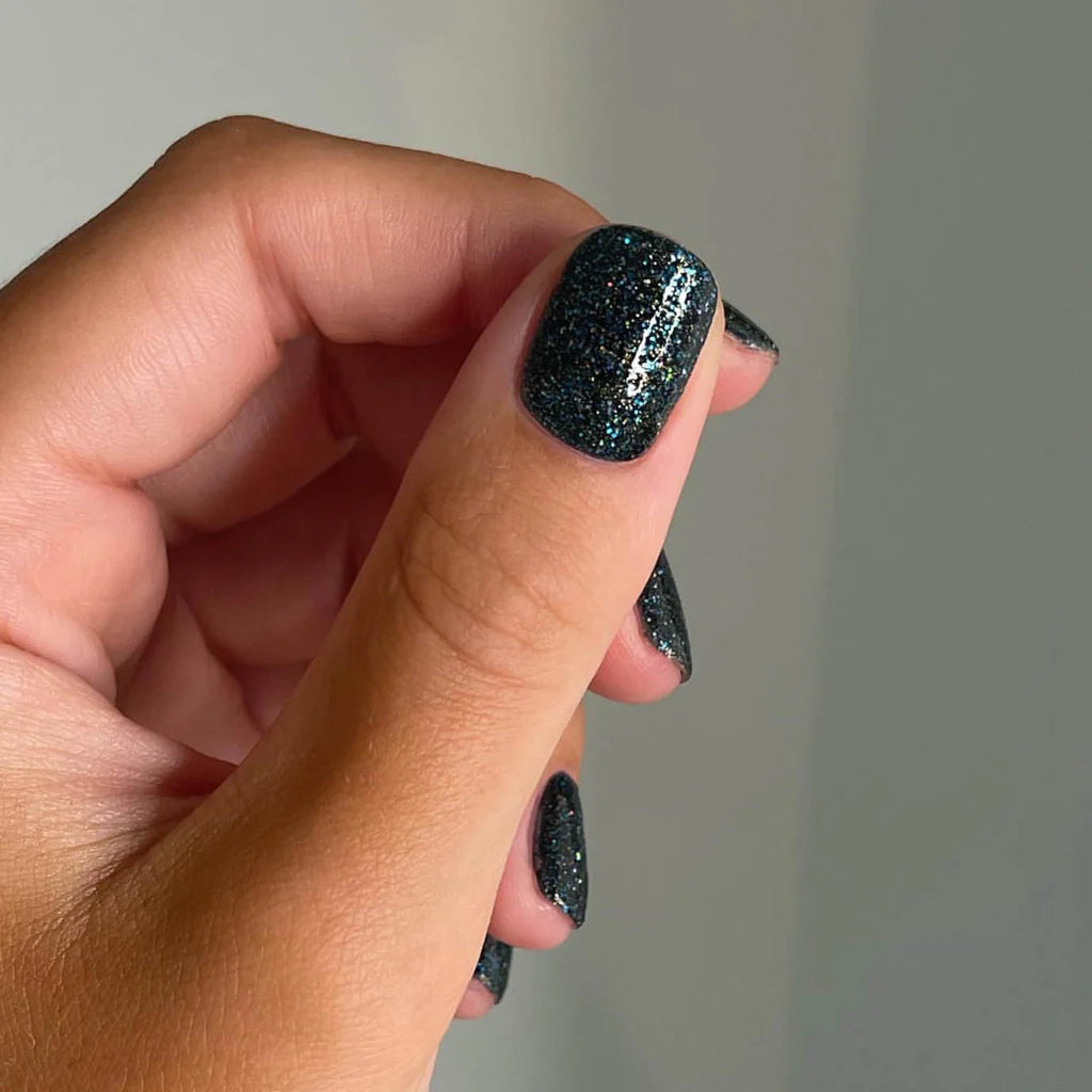Bio Sculpture Gemini Nail Polish No. 292 Spectrolite 14ml. Fingers painted with Gemini Spectrolite on light skin – breathable, iridescent dark grey polish for a modern, bold style