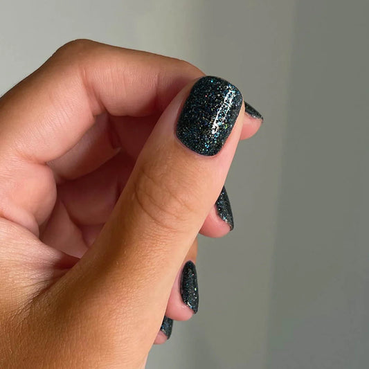 Bio Sculpture Gemini Nail Polish No. 292 Spectrolite 14ml. Fingers painted with Gemini Spectrolite on light skin – breathable, iridescent dark grey polish for a modern, bold style