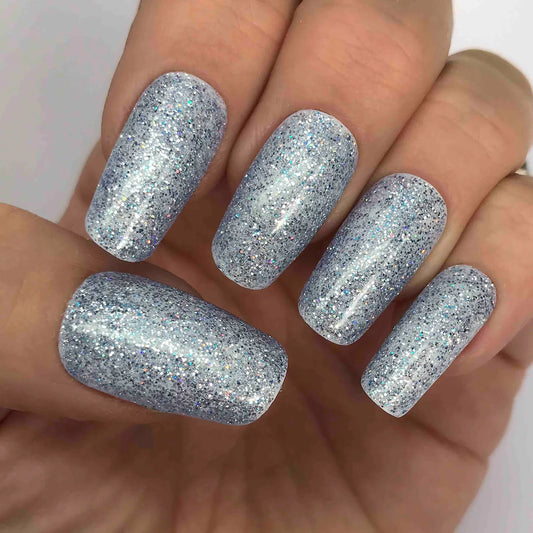 Hand wearing Bio Sculpture Gemini Nail Polish No. 264 Sapphire Song – vegan, silver and blue sapphire glitter polish for a chic, dazzling manicure