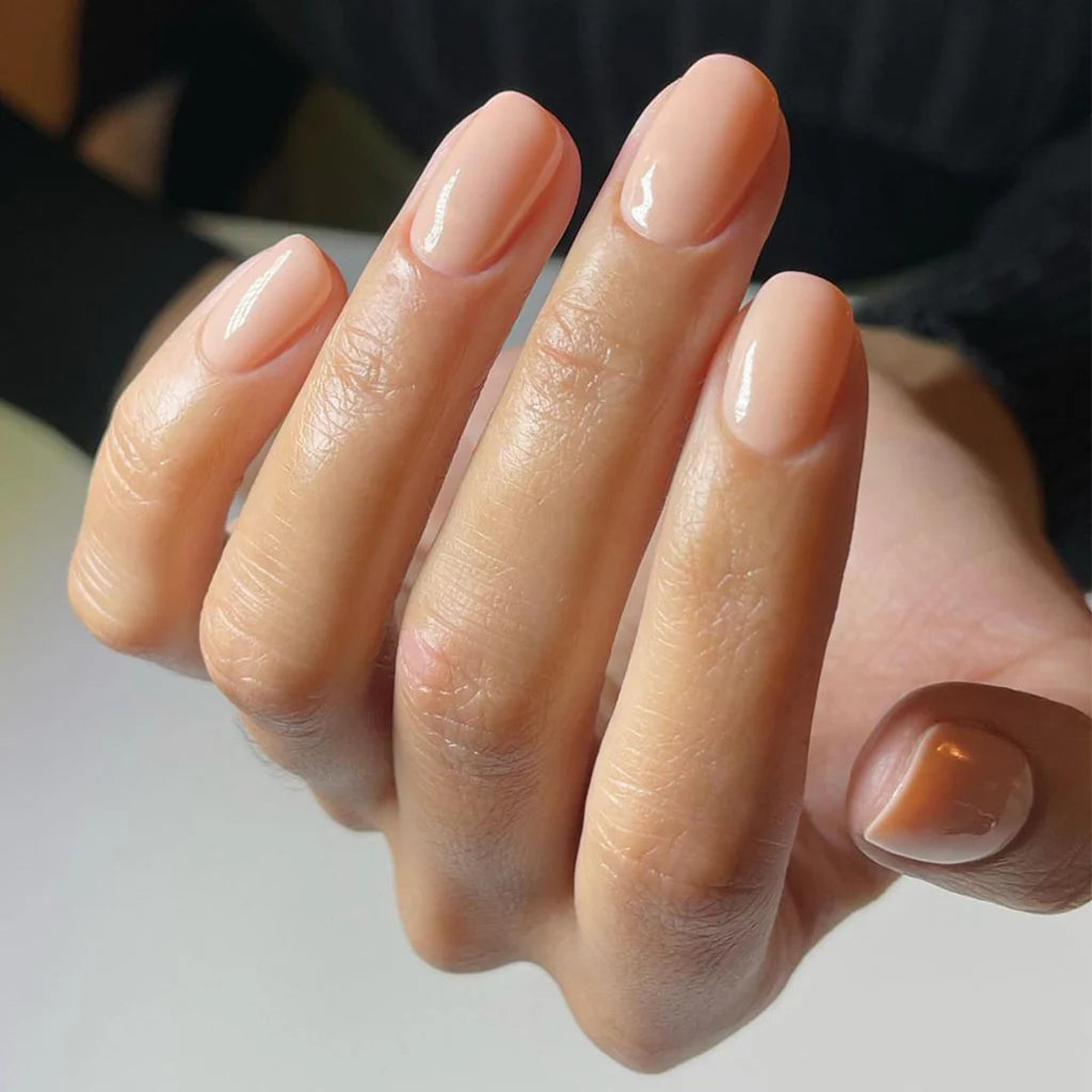 Hand wearing Bio Sculpture Gemini Nail Polish No. 210 Spun Out of Dreams – vegan, creamy peach-apricot polish for a chic, radiant nail look