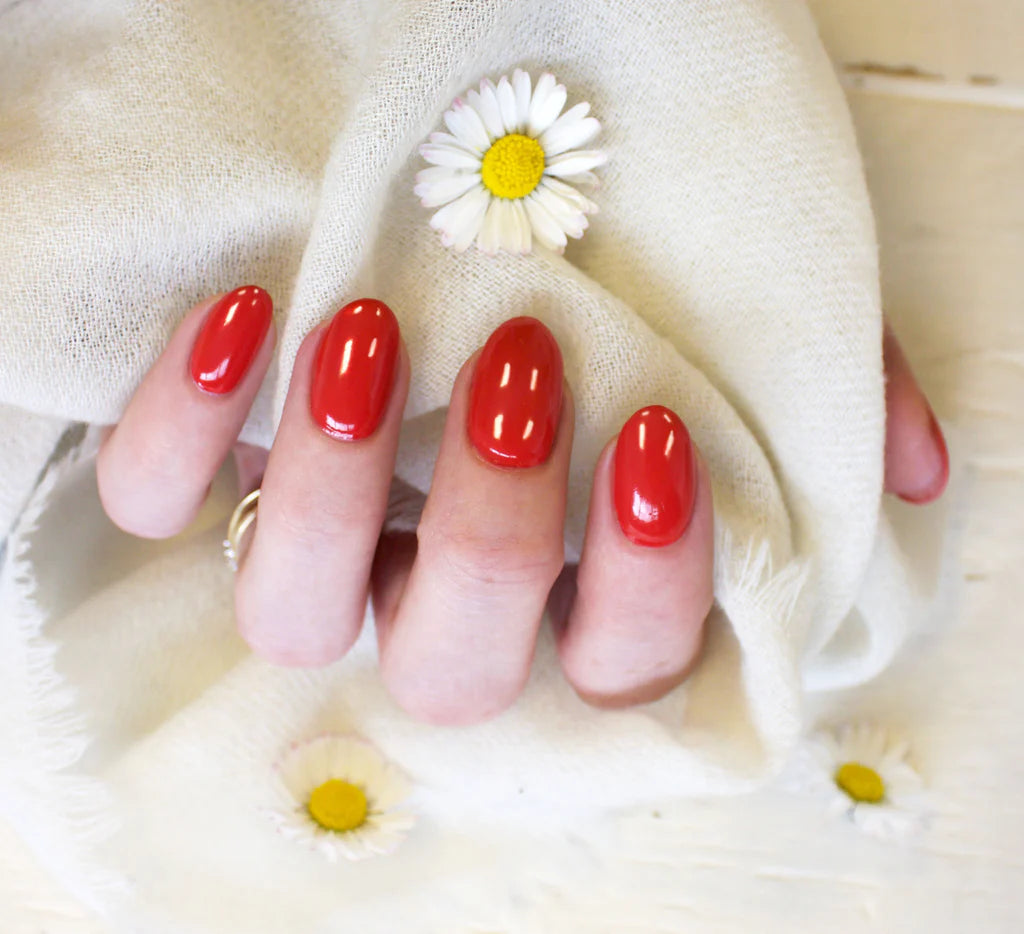 Hand wearing Bio Sculpture Gemini Nail Polish No. 16 Sunset Shimmer – vegan, radiant summer orange polish with a gold sheen for a glowing, eye-catching nail look