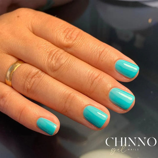 Hand wearing Bio Sculpture Gemini Nail Polish No. 120 Turquoise Tea Cup – vegan, solid bright turquoise blue polish for a striking, modern nail look