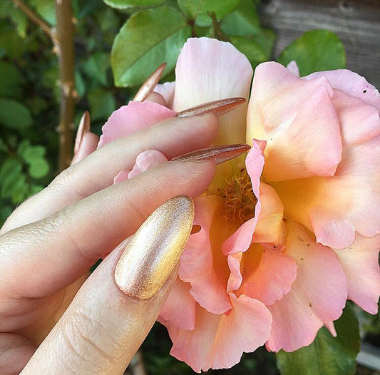 Hand wearing Bio Sculpture Gemini Nail Polish No. 169 The Rebel – vegan, pearlescent rose gold polish for a chic, radiant nail look