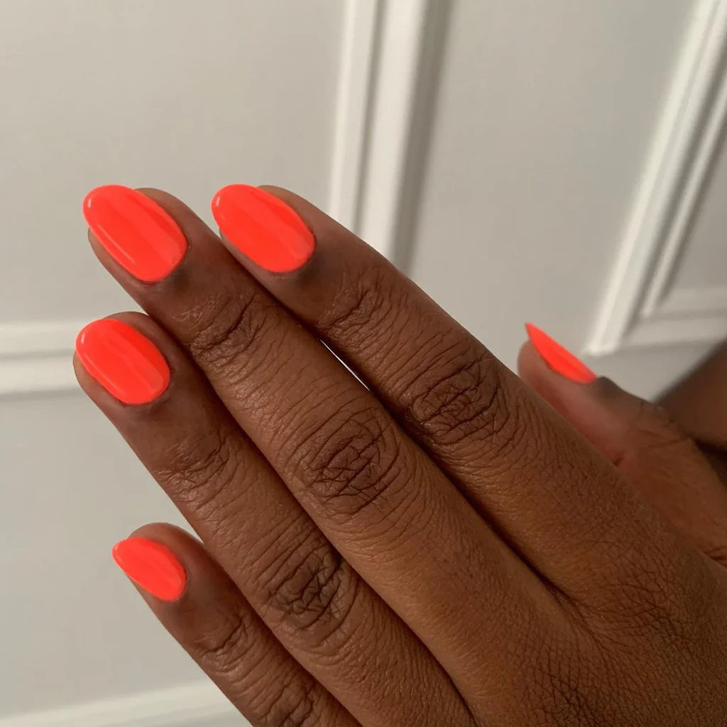 Hand wearing Bio Sculpture Gemini Nail Polish No. 208 Turn Up The Volume – vegan, neon orange polish for a vibrant, energetic nail look
