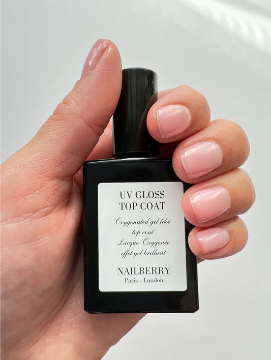 Hand holding Nailberry UV Gloss Top Coat – glossy, non-toxic top coat bottle for a professional, gel-like nail finish