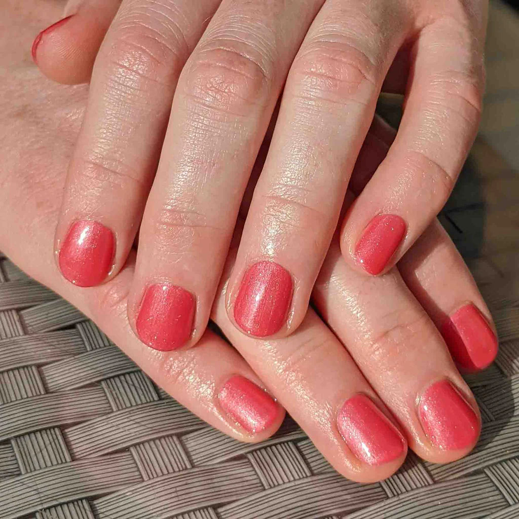 Hand wearing Bio Sculpture Gemini Nail Polish No. 110 Watermelon Freeze – bold, vegan pearlescent light watermelon pink polish for inclusive, glowing manicures