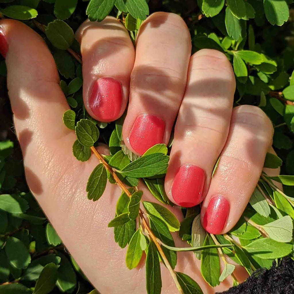Hand with light skin tone wearing Bio Sculpture Gemini Nail Polish No. 110 Watermelon Freeze – vegan, pearlescent light watermelon pink polish for a chic, radiant nail look