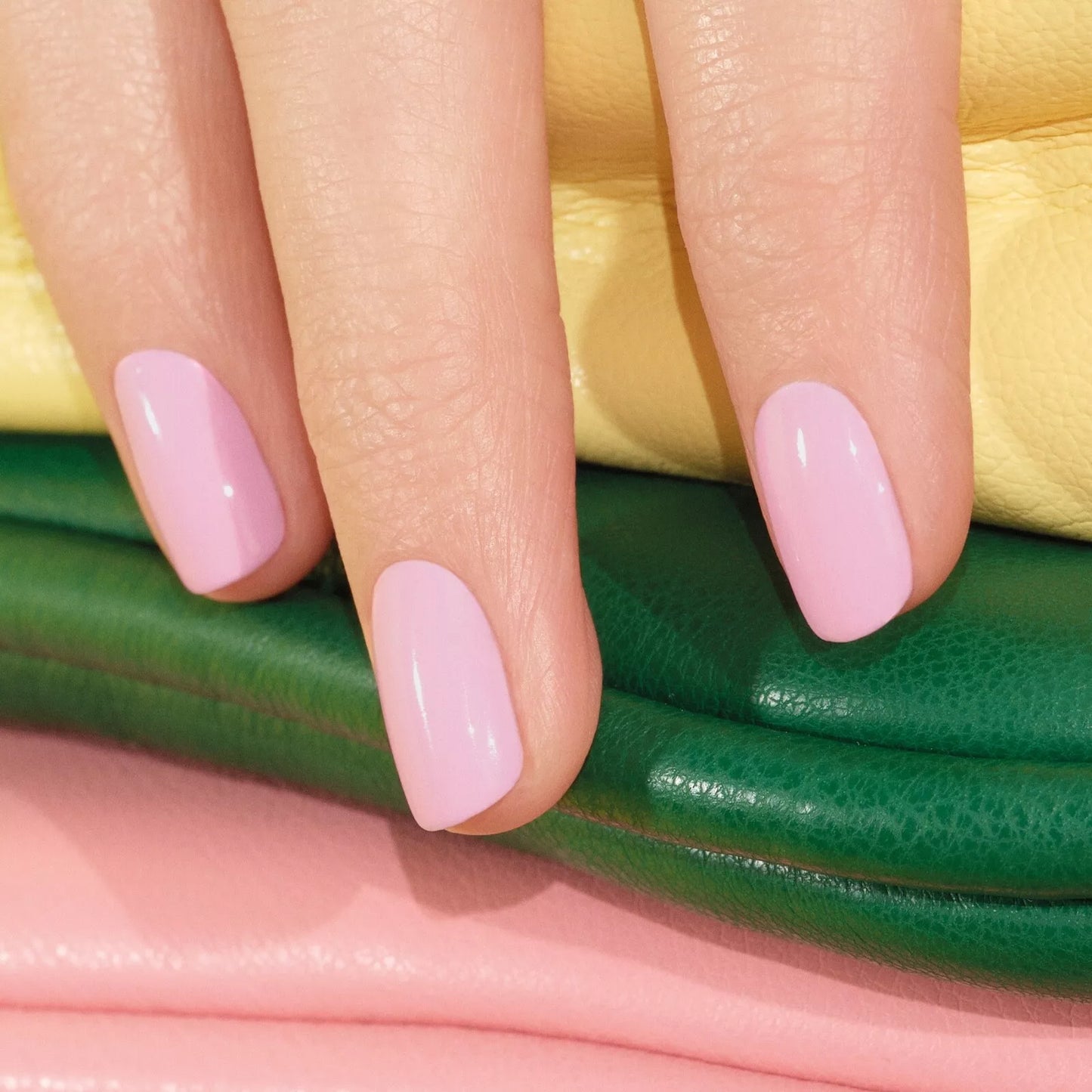 Hand with light skin tone wearing Manucurist Candy – soft, vegan pastel pink polish for a fresh, delicate manicure