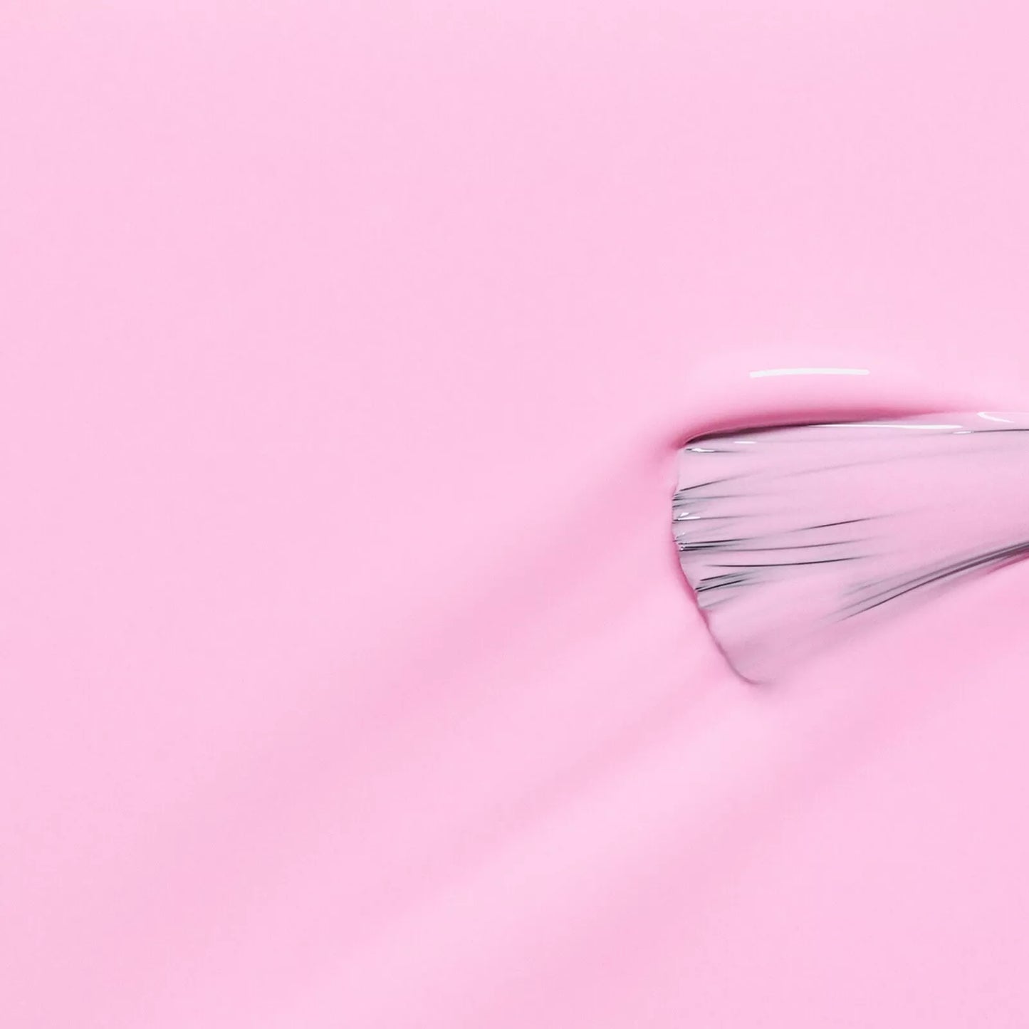 Polish brush dipped in Manucurist Candy nail polish – creamy, non-toxic pastel pink formula for smooth, even application