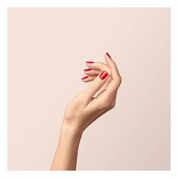 Hand wearing Manucurist Green Flash Poppy Red gel polish – bold, eco-friendly red gel alternative for a long-lasting, professional finish