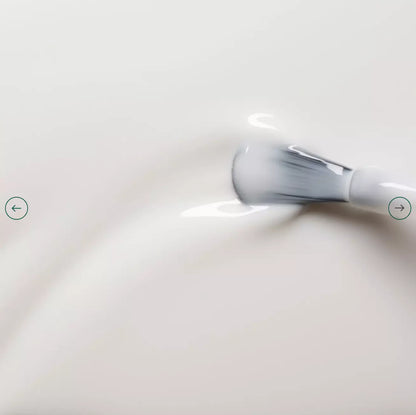 Polish brush dipped in Manucurist Milky White nail polish – creamy, non-toxic white formula for smooth application