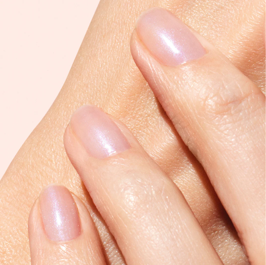 Hand with light skin tone wearing Manucurist Active Bright – clear, vegan brightening base coat for a natural, glowing manicure