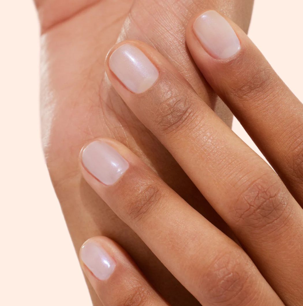 Hand with darker skin tone wearing Manucurist Active Bright – transparent, eco-friendly base coat for healthy, luminous nails