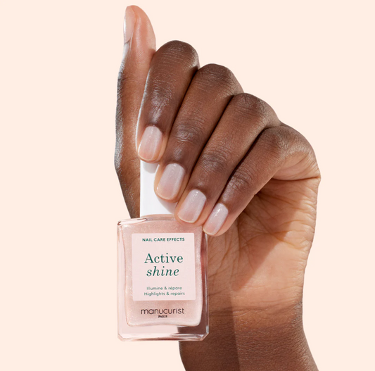 Hand holding Manucurist Paris Green Range Base Coat Active Shine – plant-based, non-toxic glossy base coat for nail care